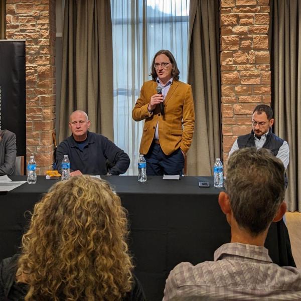 Four faculty members at a table, one holding a microphone, discuss the Israel-Hamas war.