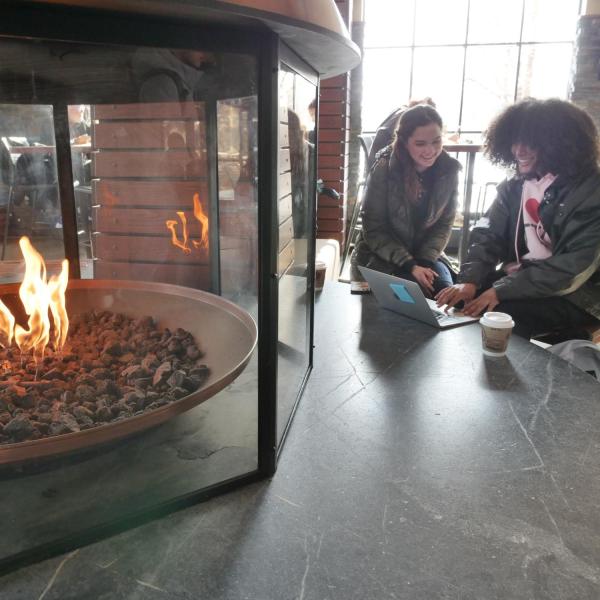 Students warm themselves on an extremely cold day at the WeatherTech Cafe fireplace