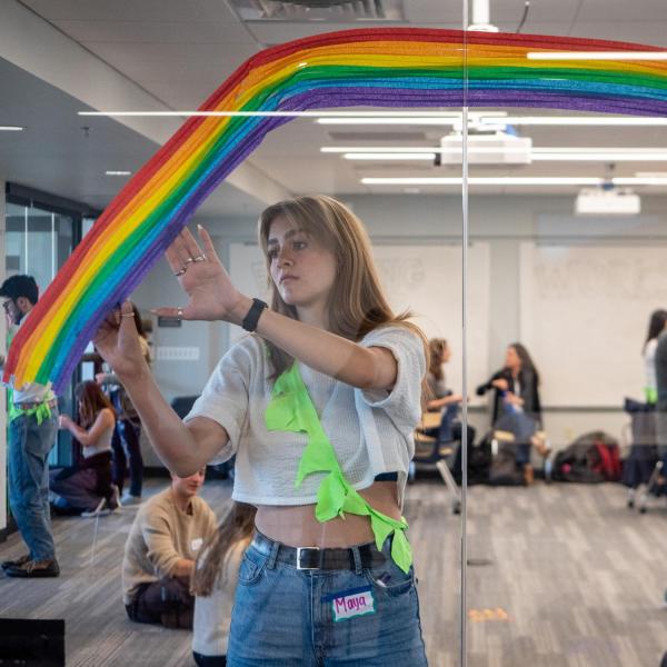 A student painting a rainbow on a window