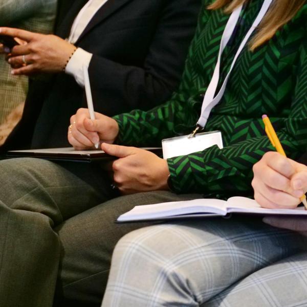 Attendees listen in and take notes during a speaker session