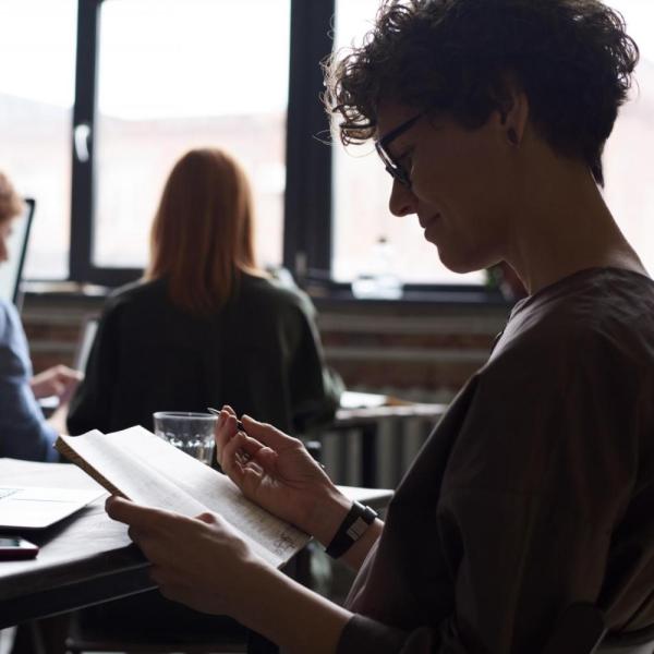 woman writing in notebook at desk in an office