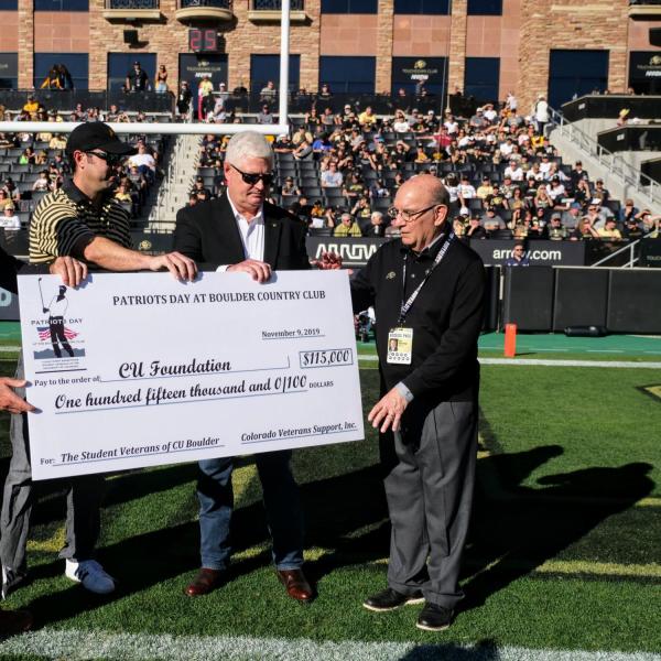 CU Boulder Chancellor Philip DiStefano, far right, and Director of Veteran and Military Affairs Stew Elliott accept a check for $115,000 to the CU Foundation from Colorado Veterans Support Incorporated and the Boulder Country Club at Folsom Field on Saturday, Nov. 9, 2019. (Photo by Glenn Asakawa/University of Colorado)