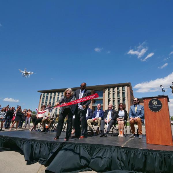 Ann Smead, left, and Brian Argrow, chair of the aerospace engineering department, cut a ribbon held by drones at a ceremony at the new Aerospace Engineering Sciences Building at CU Boulder. (Photo by Glenn Asakawa/CU Boulder)