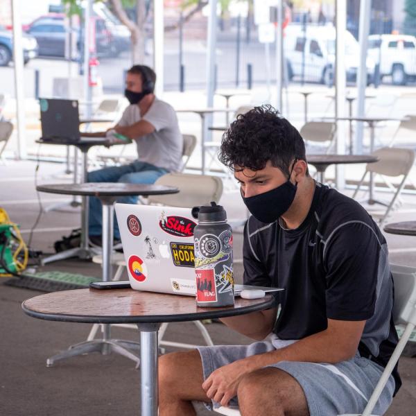 Students work in a study space tent in the Physics parking lot, all wearing facial coverings and practicing proper social distancing protocols, on the first day of the 2020 Fall semester on the CU Boulder Campus. (Photo by Glenn Asakawa/University of Colorado)