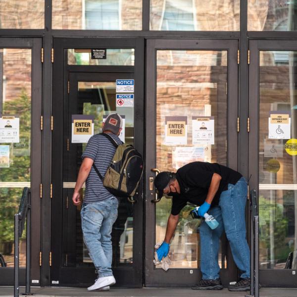 A UMC worker cleans and sanitizes the main north entrance doors. Students, staff and faculty, all wearing facial coverings and practicing proper social distancing protocols, participate in classes and study on the first day of the 2020 Fall semester on the CU Boulder Campus. (Photo by Glenn Asakawa/University of Colorado)