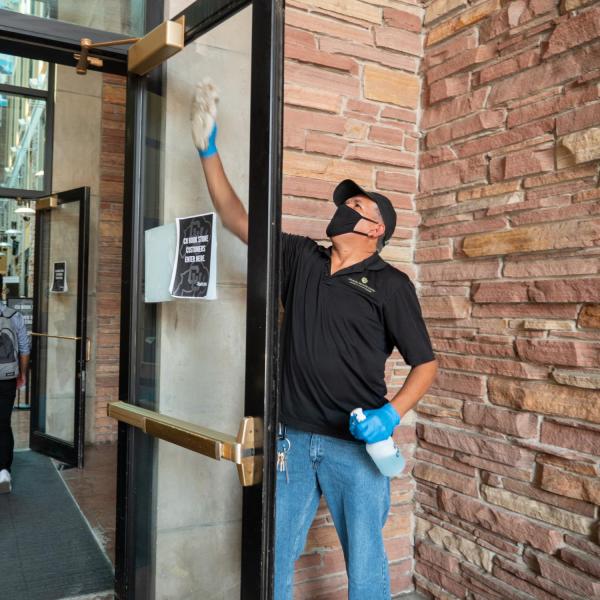 A UMC worker cleans and sanitizes the main north entrance doors. Students, staff and faculty, all wearing facial coverings and practicing proper social distancing protocols, participate in classes and study on the first day of the 2020 Fall semester on the CU Boulder Campus. (Photo by Glenn Asakawa/University of Colorado)