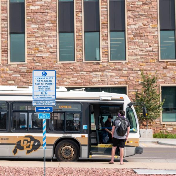 Students practice social distancing at the bus stop by the CASE building. (Photo by Glenn Asakawa/University of Colorado)