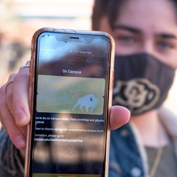CU Boulder student Matias Mendez holds up his phone showing the Buff Pass website as he returns to campus for the start of in-class instruction. (Photo by Glenn Asakawa/University of Colorado)