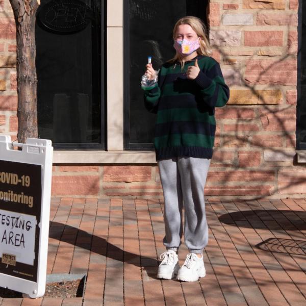 CU Boulder first year student Lily Fletcher flashes a thumbs-up sign after providing her saliva for her first COVID-19 test after moving back into the Kittredge complex on Feb. 7, 2021. (Photo by Glenn Asakawa/University of Colorado)