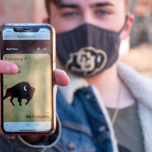 CU Boulder student Matias Mendez holds up his phone showing the Buff Pass website as he returns to campus for the start of in-class instruction. (Photo by Glenn Asakawa/University of Colorado)