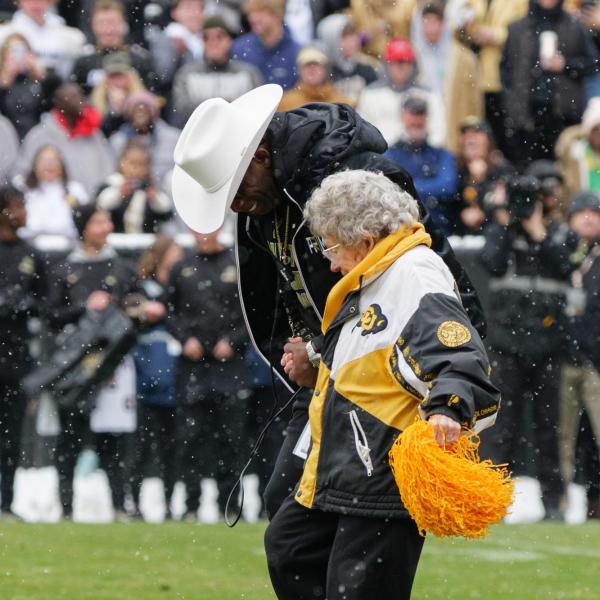 Deion Sanders, “Coach Prime” helps honorary captain and longtime Buff fan Peggy Coppom kick off the ball