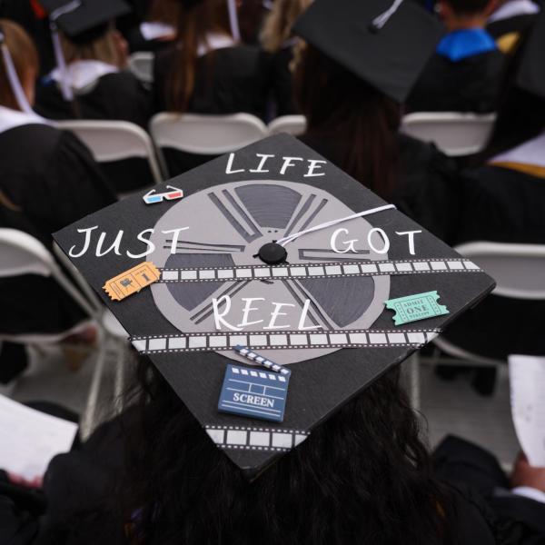 Graduation cap with a film reel painted on it that says 'Life just got reel'