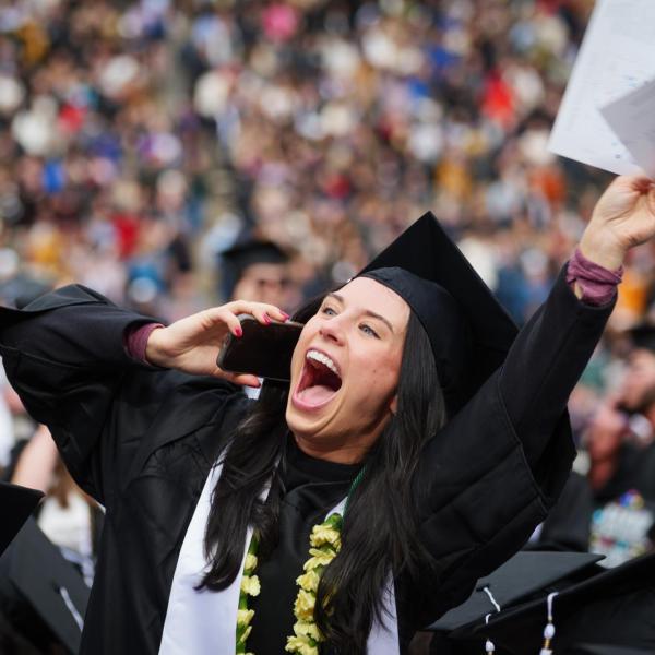 Graduate looks up at friends and family in the stands