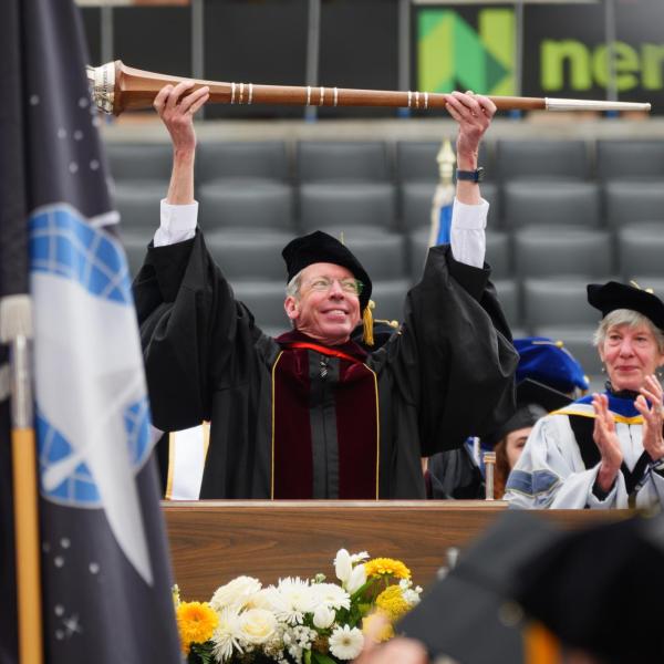 Commencement Marshal Bud Coleman lifts the ceremonial mace above his head