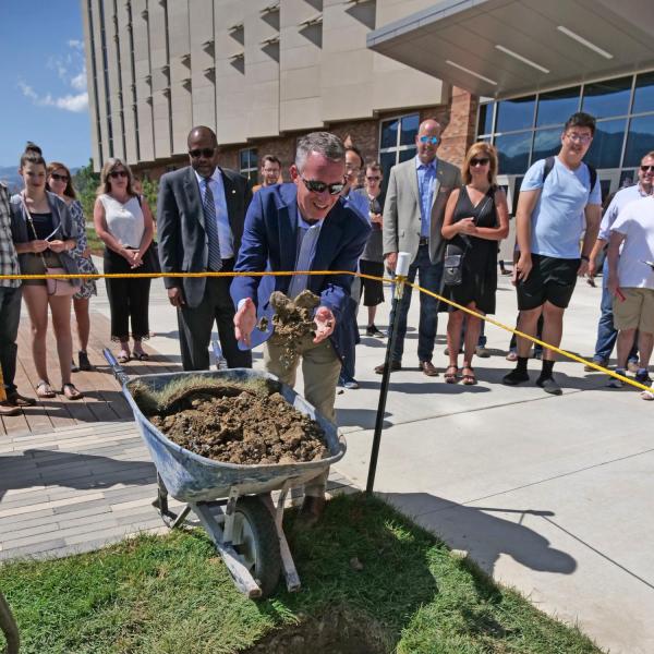 Dean Bobby Braun tosses dirt on a time capsule in front of CU Boulder's new Aerospace Engineering Sciences Building.