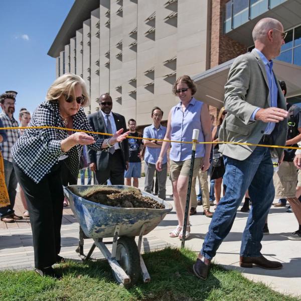 Donor Ann Smead tosses dirt on a time capsule in front of CU Boulder's new Aerospace Engineering Sciences Building.