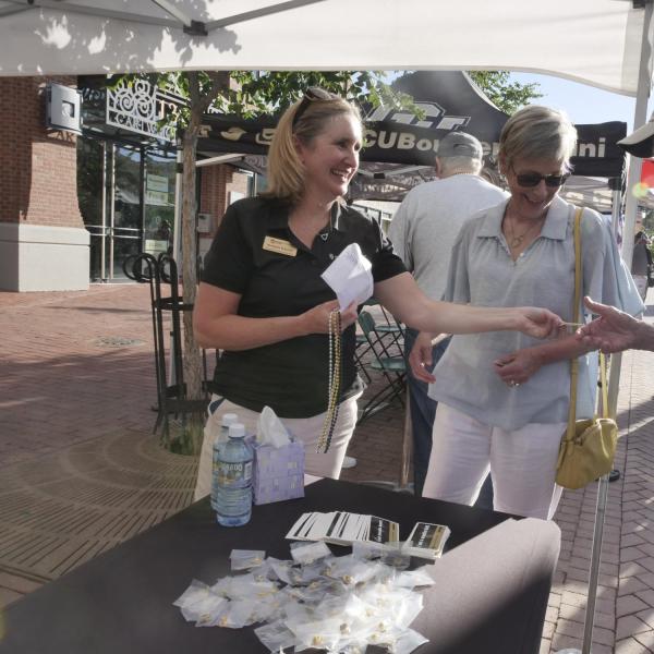 Volunteer speaks with visitors at a CU table on Pearl Street