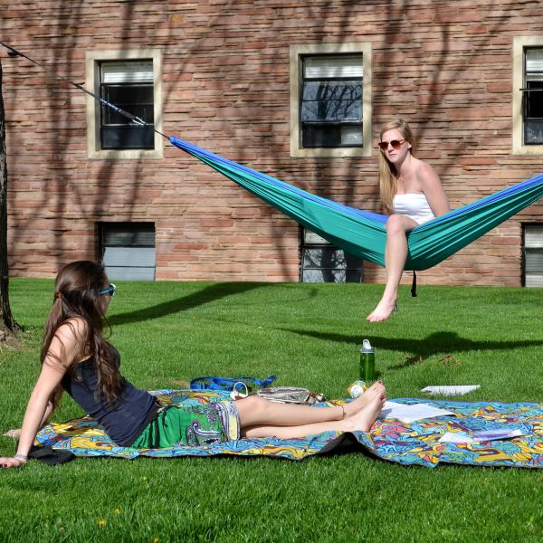 Students lounge outside in hammocks, on blankets