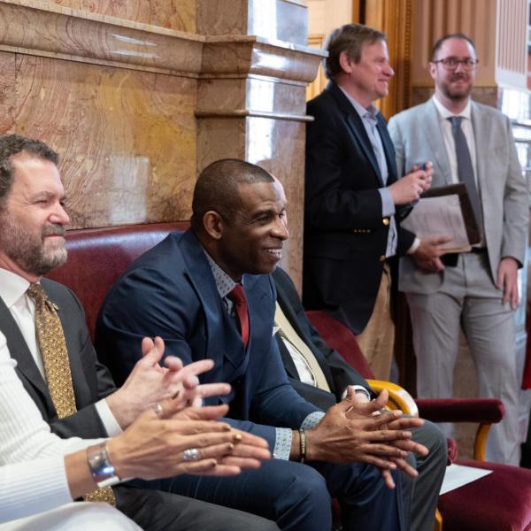 Deion Sanders sits between CU President Todd Saliman, left, and CU Boulder Chancellor Phil DiStefano, while being honored in the Senate Chamber