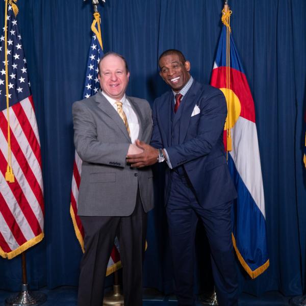 Gov. Jared Polis poses with CU football coach Deion Sanders in Polis’ office at the state Capitol