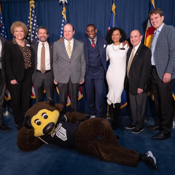 Gov. Jared Polis poses with Deion Sanders and other CU and higher ed leadership in Polis’ office at the state Capitol
