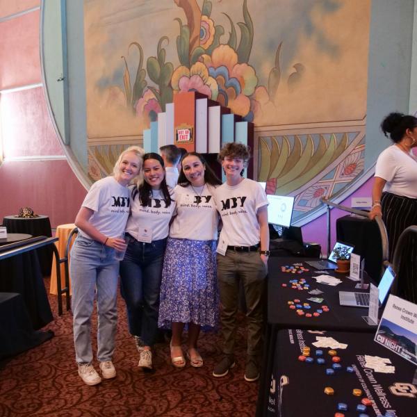 Student volunteers promoting the Renee Crown Wellness Institute pose by their table at the CU Night in Downtown Boulder event at Boulder Theater
