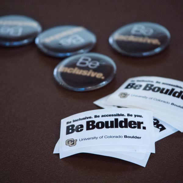 Be Inclusive pins and Be Boulder stickers
