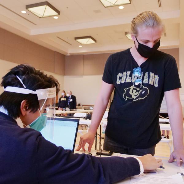 Owen Arnold, right, a junior media production student from Chicago, gets instructions from ballot judge Luis Molina, a first year international affairs student, at a CU Boulder polling place. (Photo by Casey A. Cass/University of Colorado)