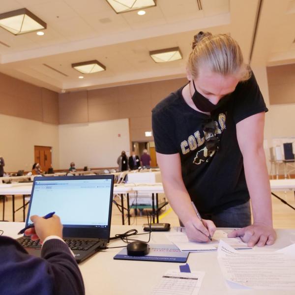 Owen Arnold, right, a junior media production student from Chicago, gets instructions from ballot judge Luis Molina, a first year international affairs student, at a CU Boulder polling place. (Photo by Casey A. Cass/University of Colorado)
