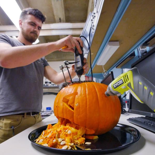 Alex Vinson, Idea Forge staff member, puts the finishing touches on his department's pumpkin carving entry. Photo by Glenn Asakawa.