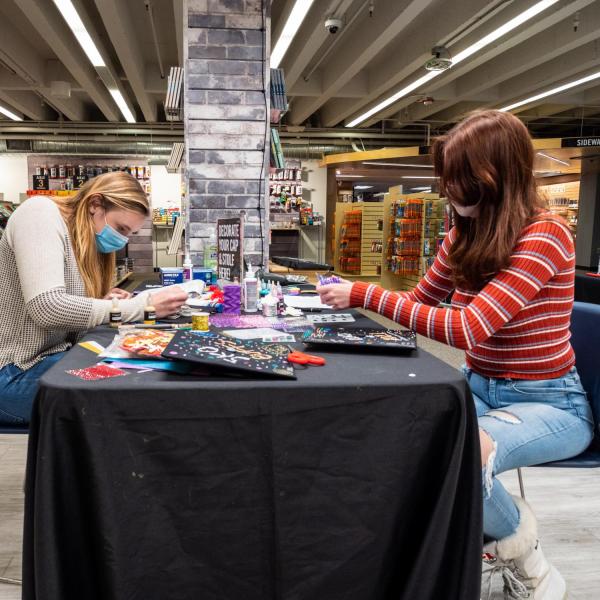 Students decorate their graduation caps and stoles at the University Bookstore. (Photo by Patrick Campbell/University of Colorado)
