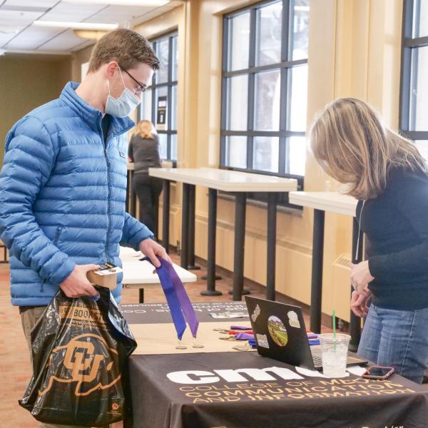 Students sign the Class of 2021 banner and pick up regalia at the 2021 Gear Grab event. (Photo by Casey Cass/University of Colorado)