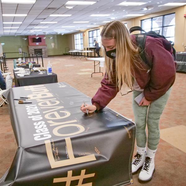 Students sign the Class of 2021 banner and pick up regalia at the 2021 Gear Grab event. (Photo by Casey Cass/University of Colorado)