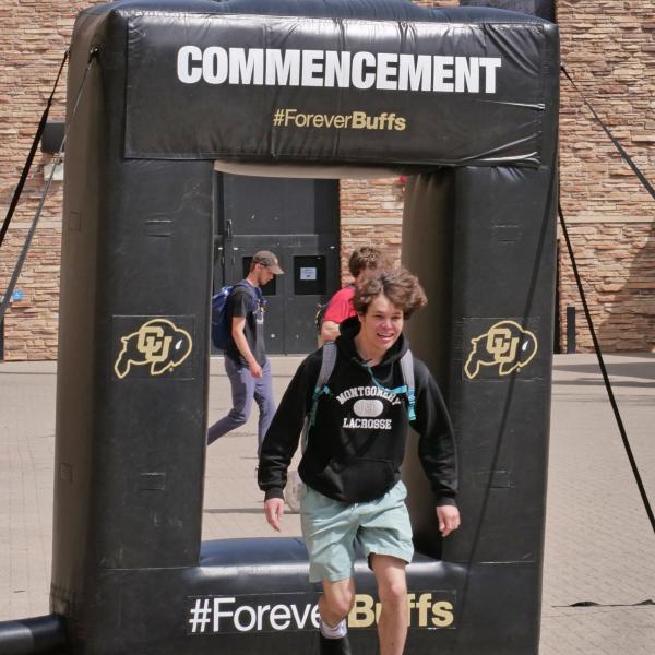 A student hops through an inflatable frame for graduate photo ops on campus
