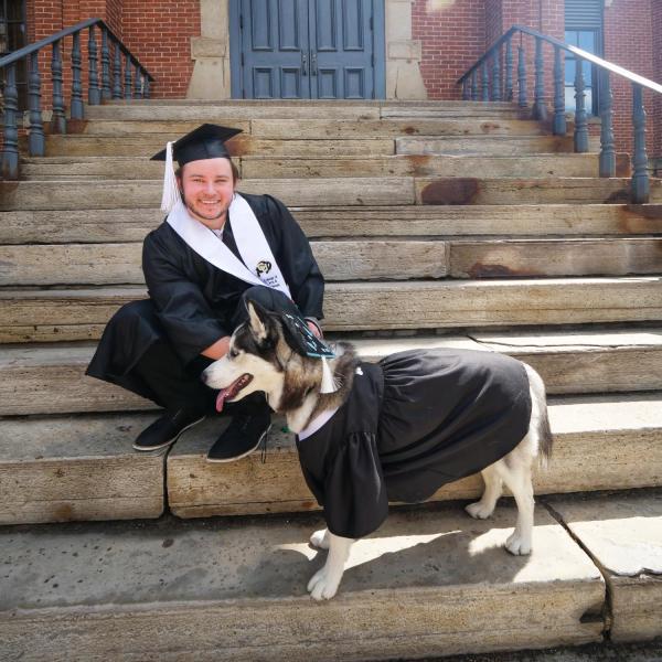 Michael Hasenkamp poses on the front steps of Old Main with his dog, Luna Lovegood. (Photo by Glenn Asakawa/University of Colorado)