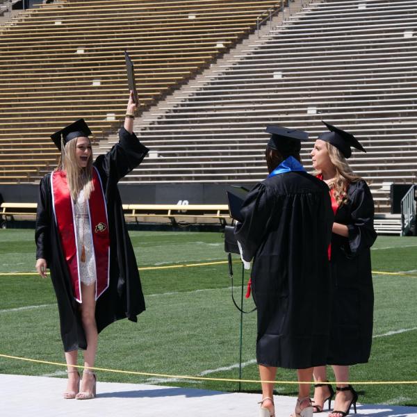 Graduates celebrate after getting their photo taken at Folsom Field during CU Boulder’s Graduate Appreciation Days events. (Photo by Glenn Asakawa/University of Colorado)
