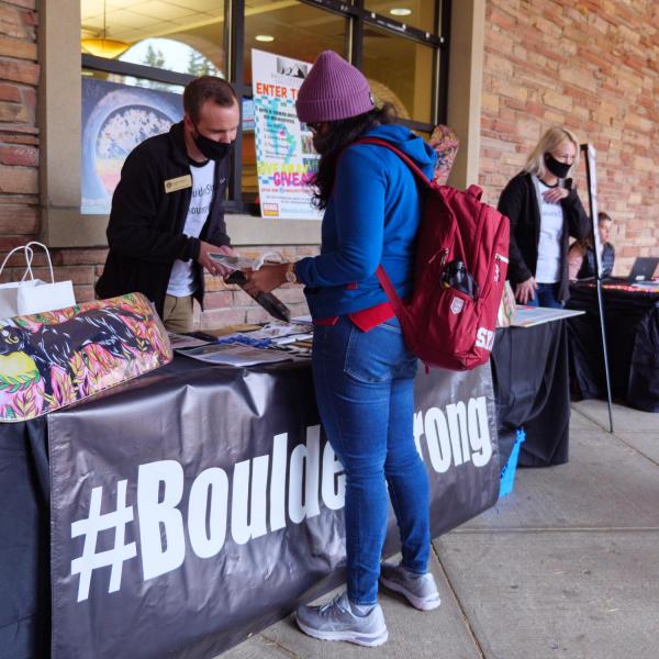 A student looks over a table staffed by the #BoulderStrong Resource Center at the Health Hut event during the 2021 Health and Wellness Summit on the CU Boulder campus. (Photo by Glenn Asakawa/University of Colorado)