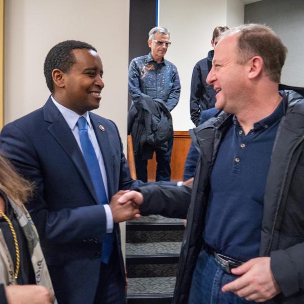 Colorado Gov. Jared Polis, right, greets U.S. Representative Joe Neguse at a ceremonial swearing-in event at Colorado Law. Photo by Glenn Asakawa.
