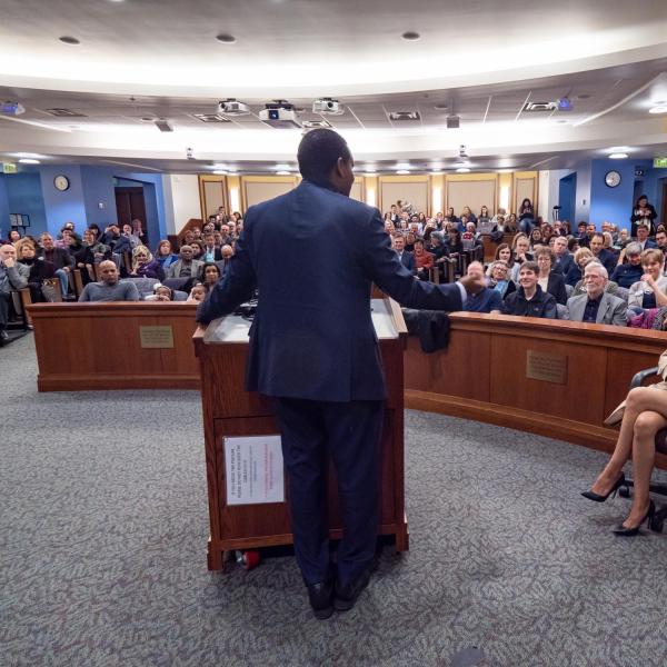 Andrea Neguse, holding her daughter, Natalie, right, listens to Joe Neguse, U.S. Representative Joe Neguse speak following a swearing-in event. Photo by Glenn Asakawa.