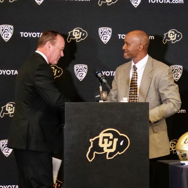 New CU football head coach Karl Dorrell, right, shakes hands with Athletic Director Rick George introduces him at a press conference at the Dal Ward Center at Folsom Field. (Photo by Glenn Asakawa/University of Colorado)