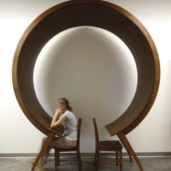 Woman sits at and under a unique circular table