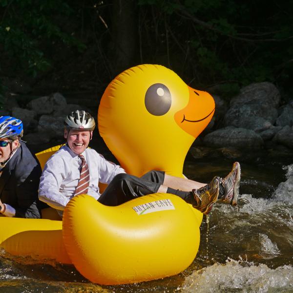 Smiling CU alumnus Chris Achatz and passenger ride the creek to work