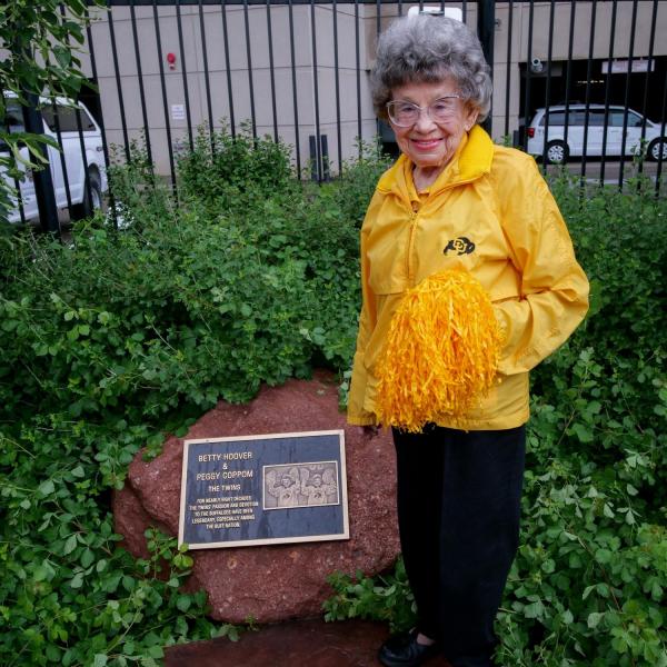 Peggy Coppom stands next to a plaque honoring her and her late twin sister, Betty Hoover. (Photo by Glenn Asakawa/University of Colorado)