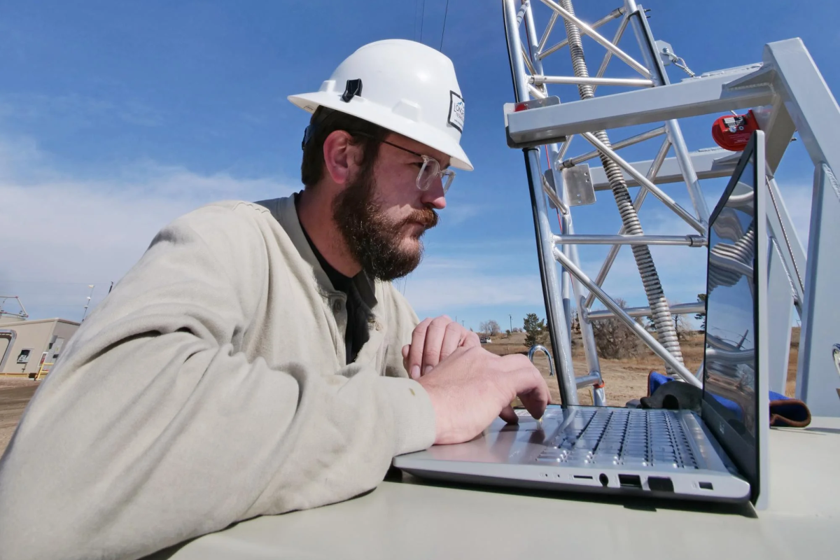 A technician inspects a high-tech laser on a tower in a natural gas site in Colorado