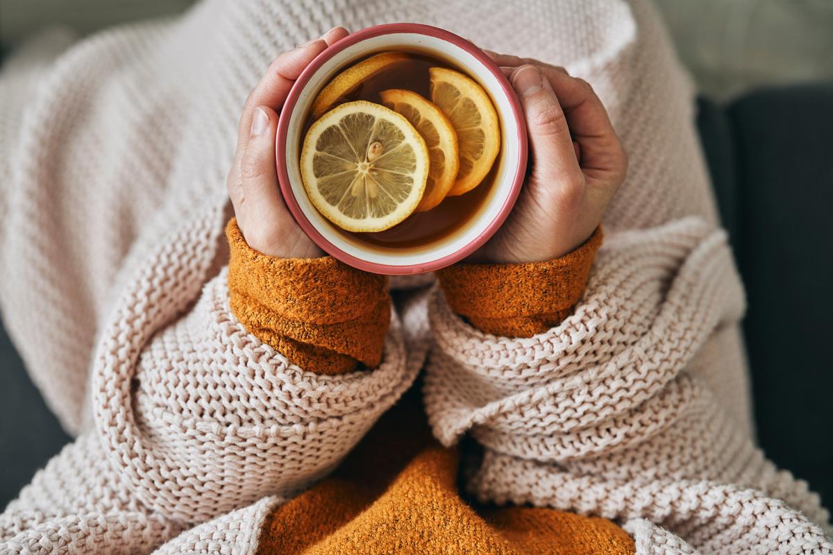 person drinking a cup of hot tea with lemon