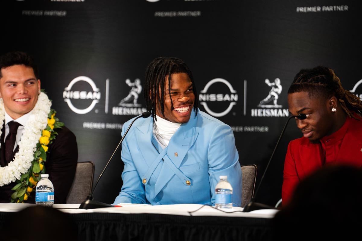 Travis Hunter sits at a table, smiling and wearing a powder blue suit.