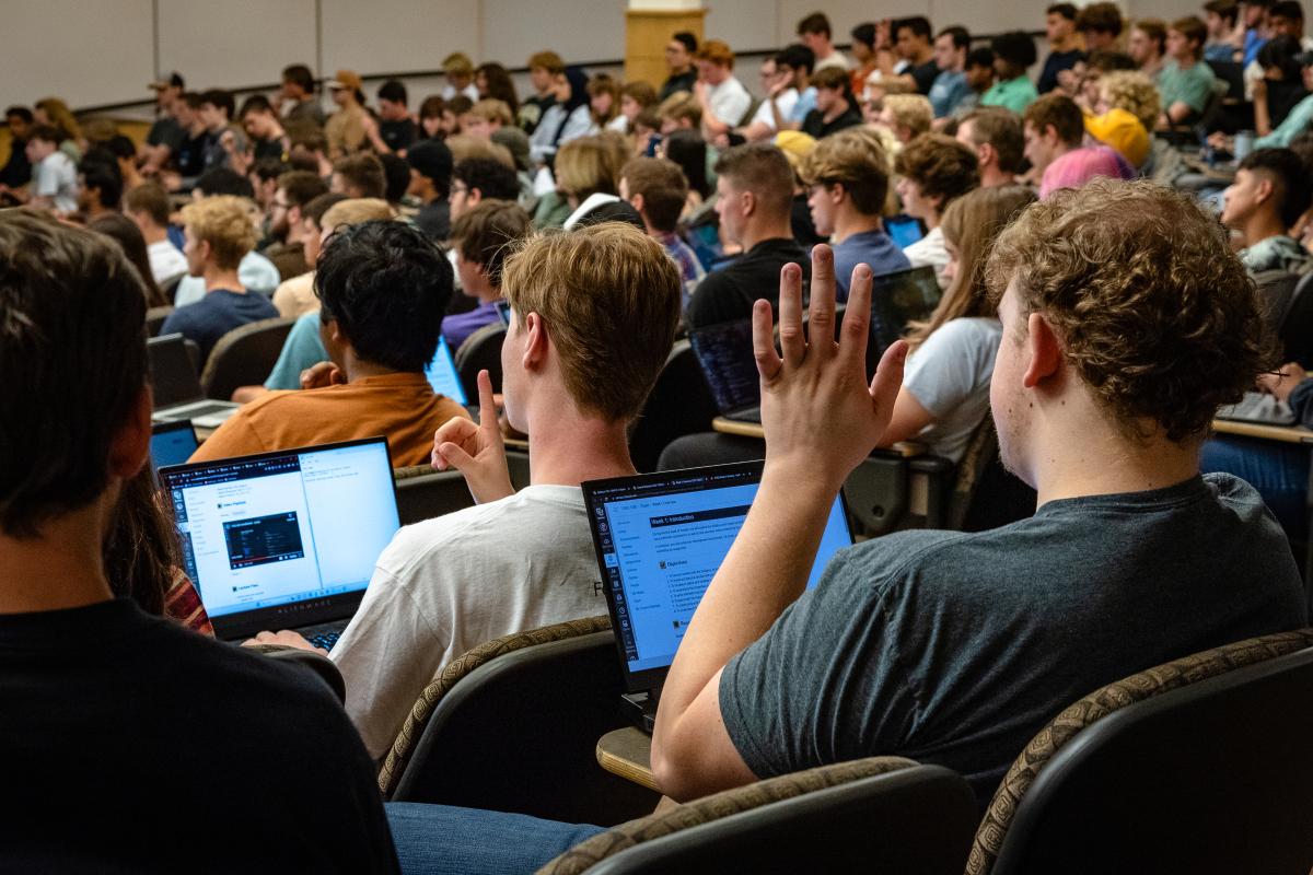 Student raising hand in lecture hall