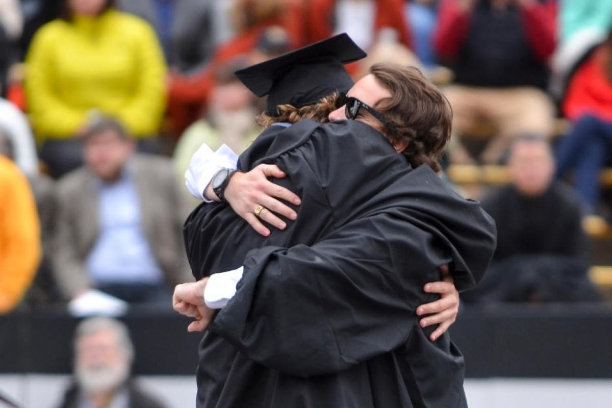 two graduates hugging after commencement ceremony