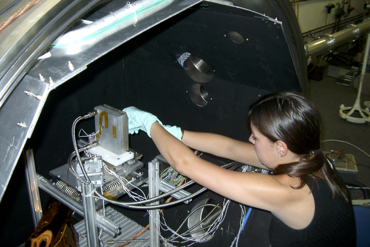 Woman wearing gloves works on scientific equipment
