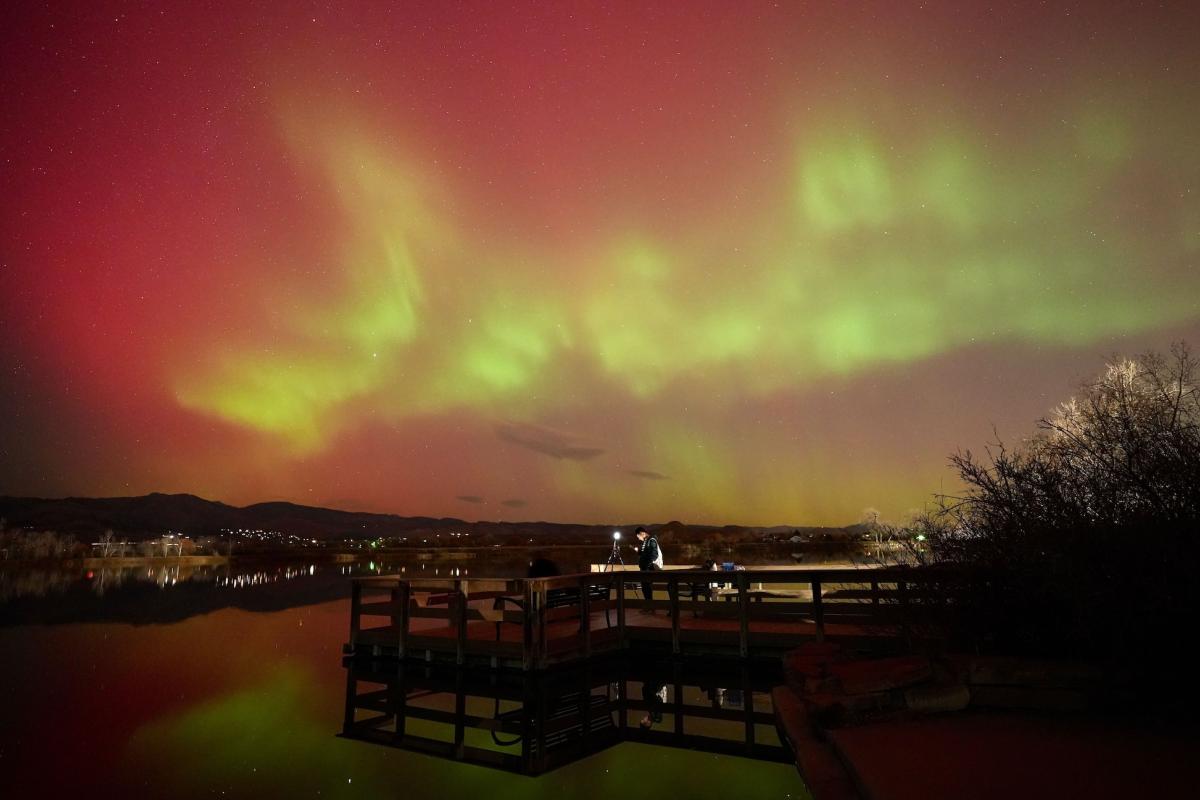 A dock on a lake seen at night with the sky glowing above it